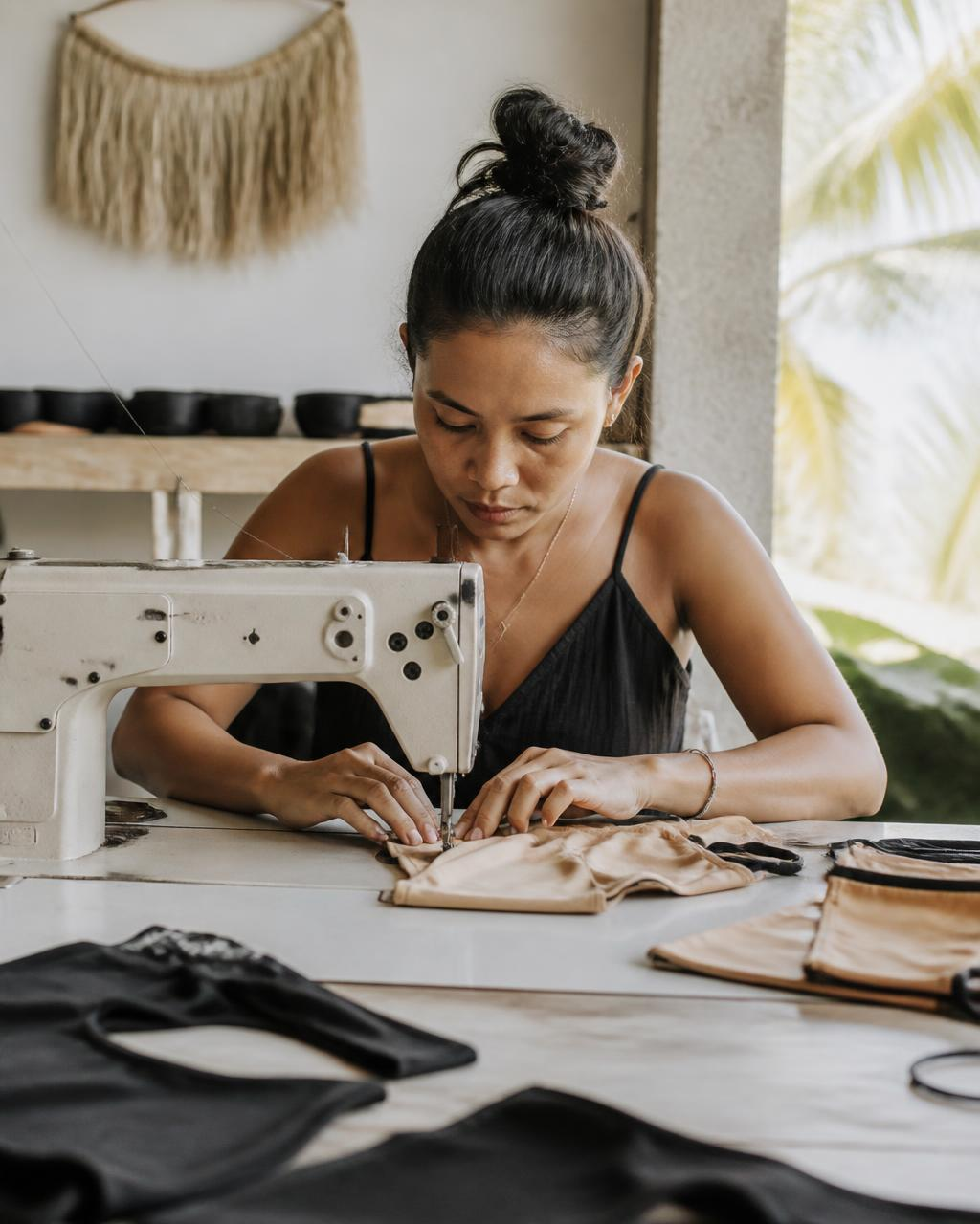 Team member sewing a bikini at a sewing machine in the Bali Swim atelier